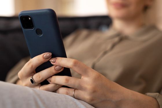 Pessoa segurando o celular, sentada no sofá.
